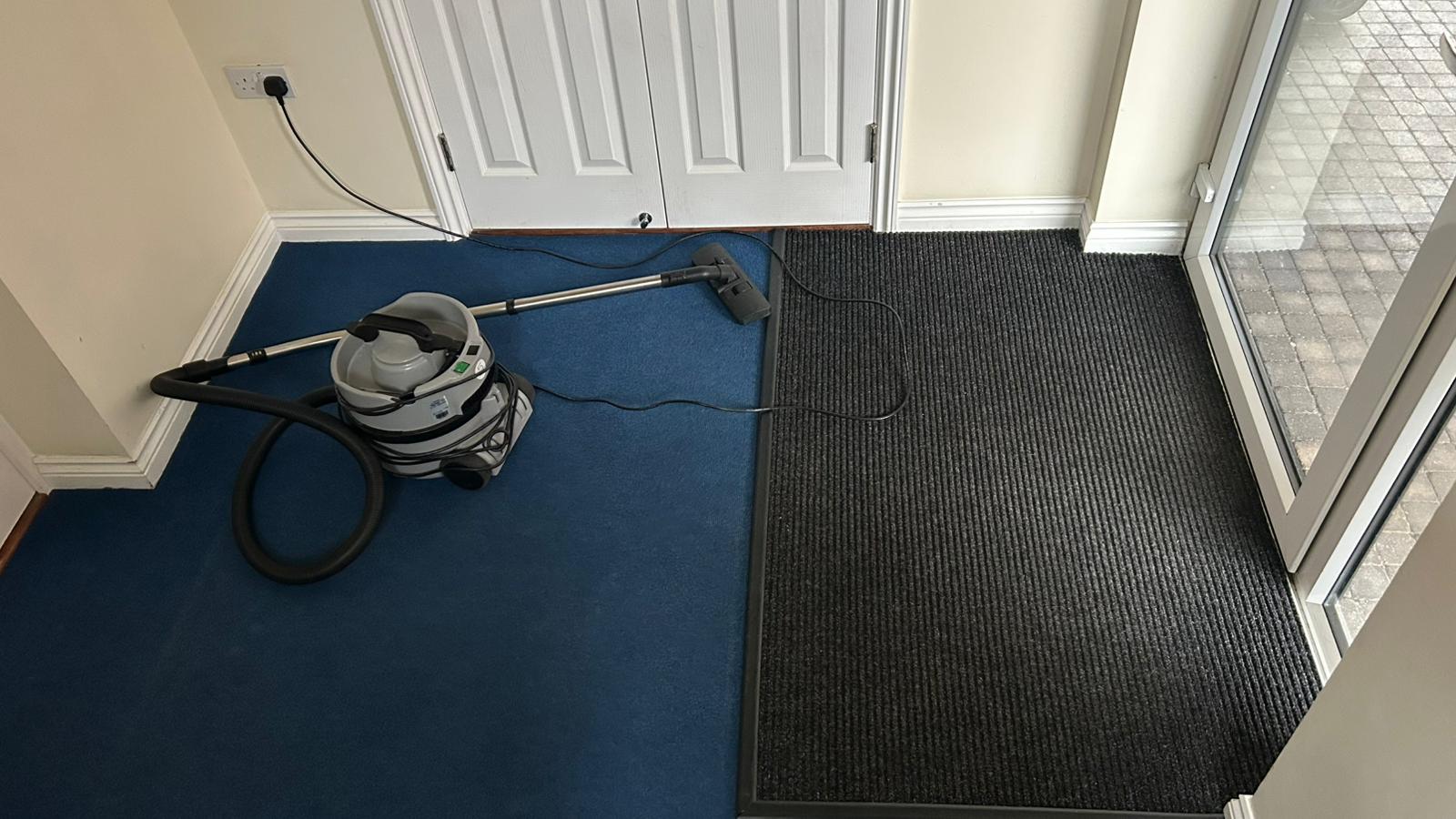 Block cleaning contractors using a hoover to clean the staircase of a building.