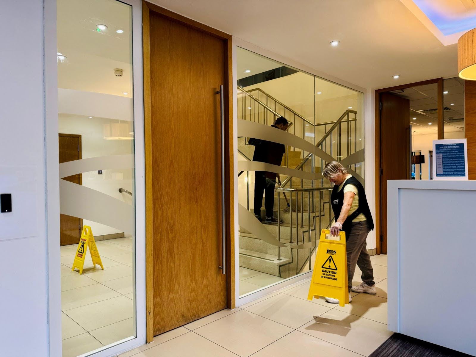 A cleaner adding a wet sign to warn people after providing professional commercial cleaning services.