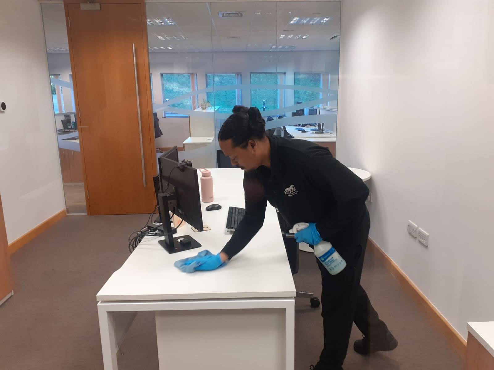A cleaner who has been transferred to another company through the TUPE transfer legislation cleaning a desk surface.